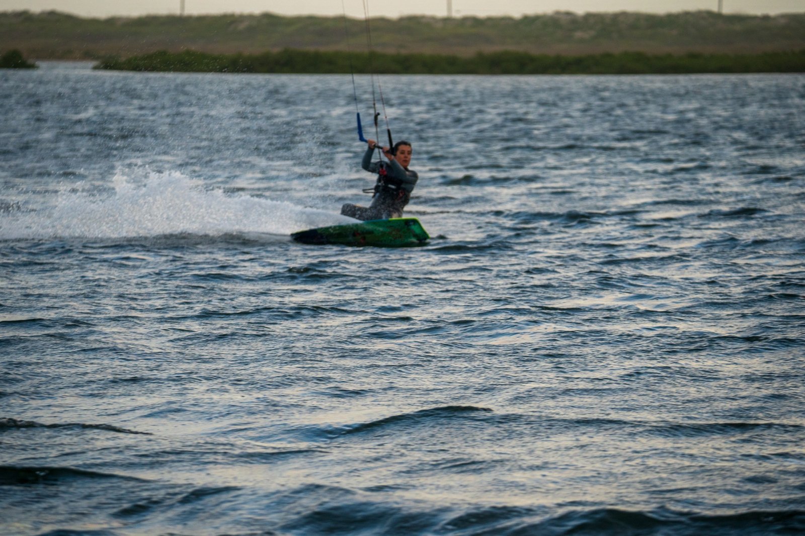 A kiteboarder carving across the water