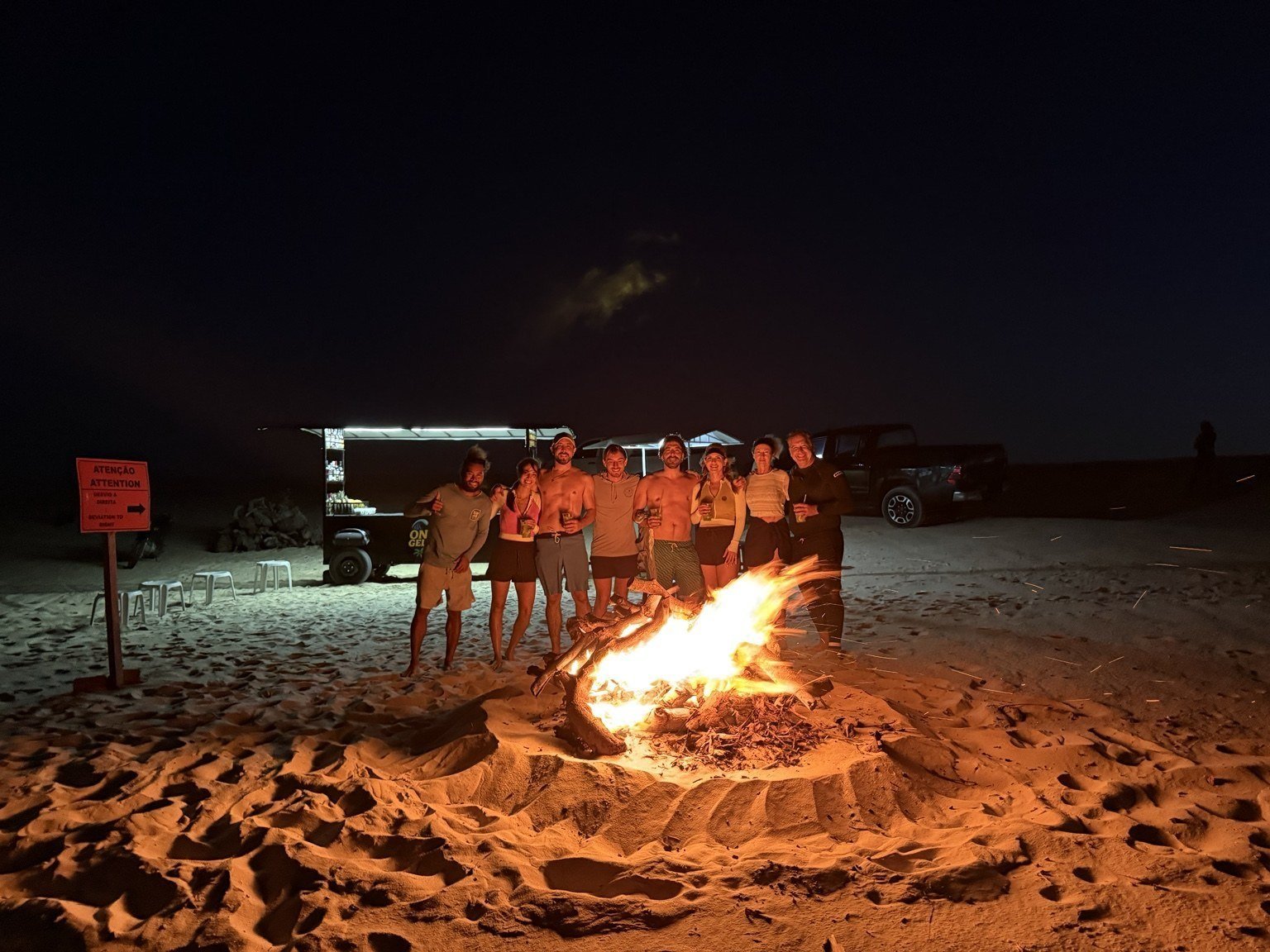 Camp friends around a beach bonfire