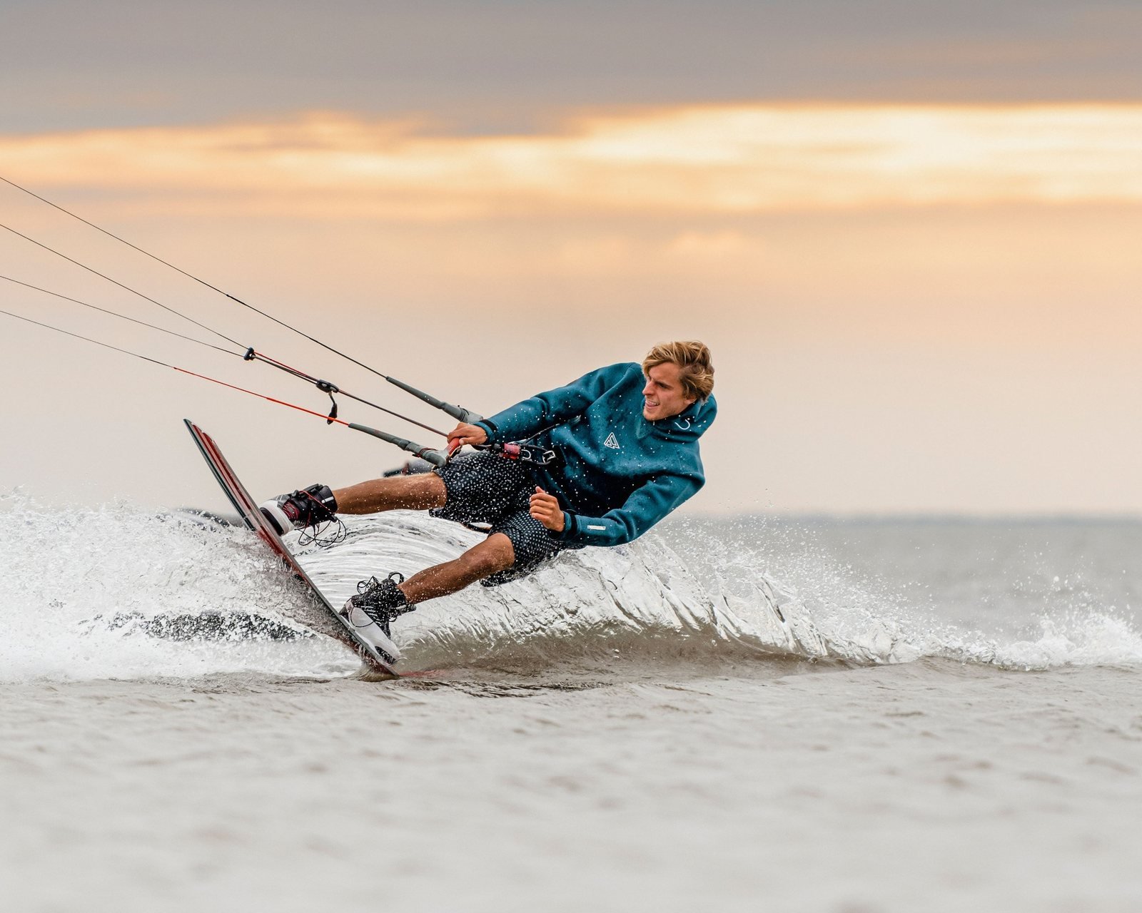 Kiteboarder carving through the spray at sunset