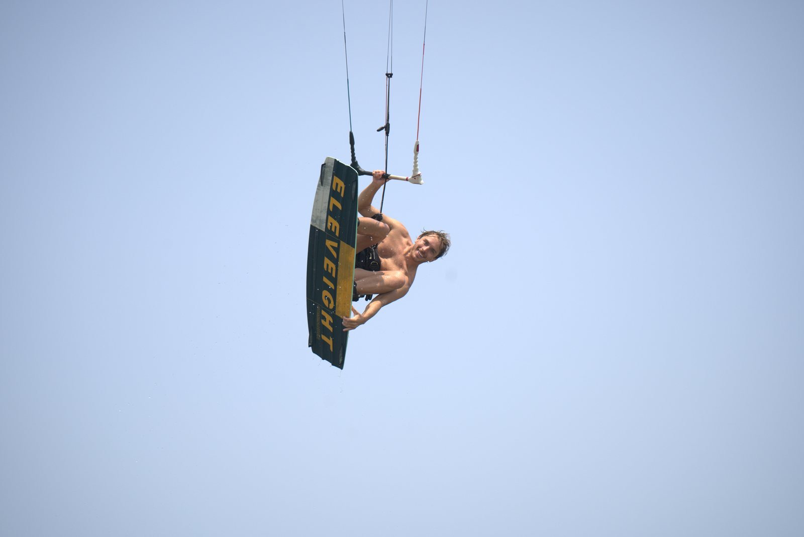 Kiteboarder holding the board during a high jump