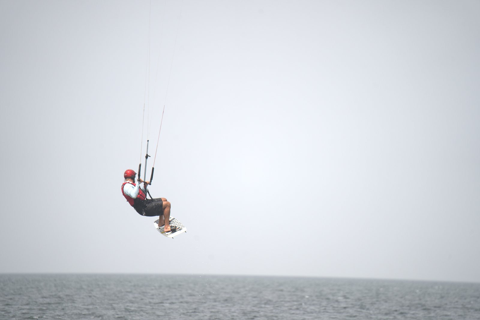 Kiteboarder jumping above the sea with a red helmet