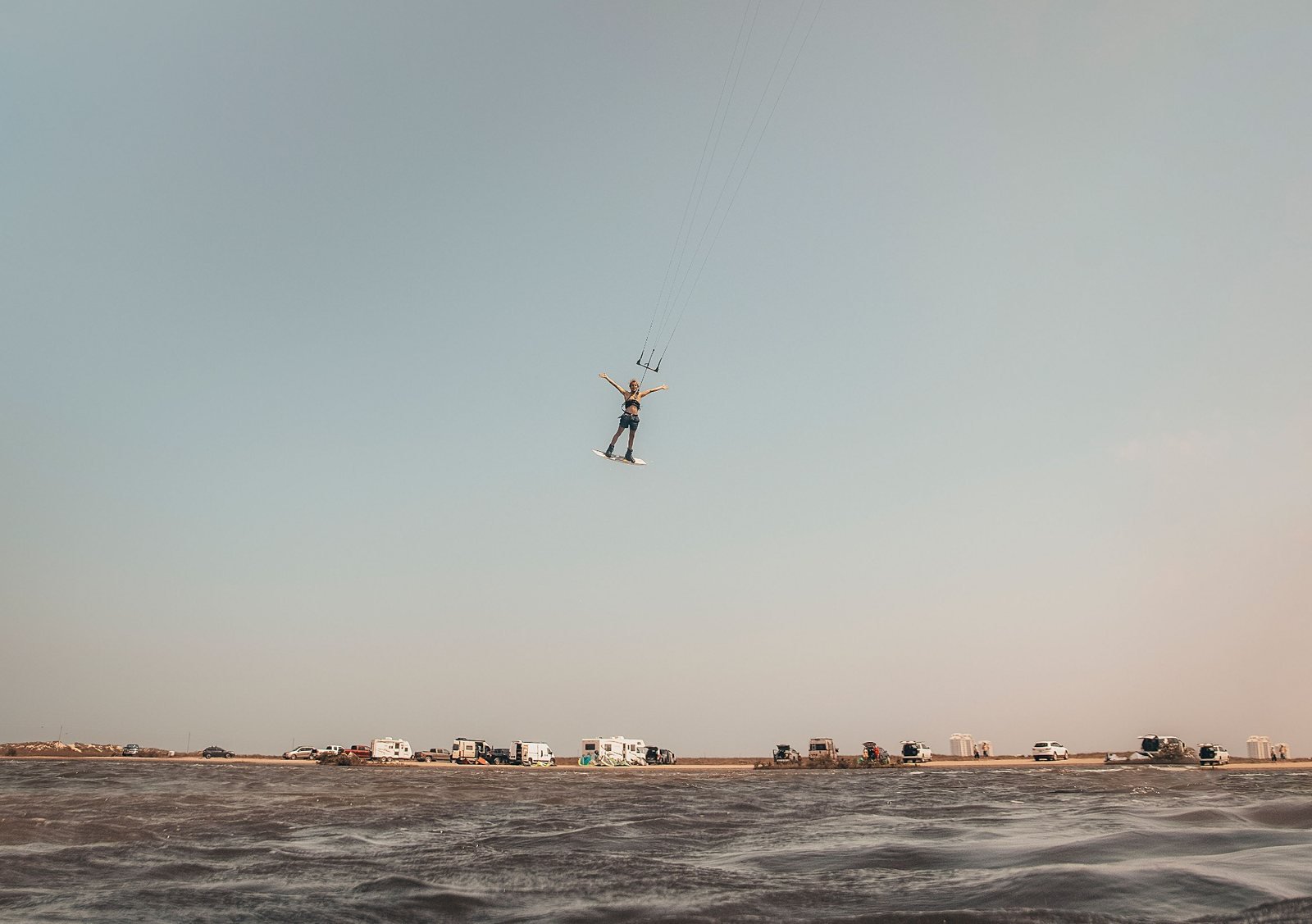 Kiteboarder jumping high above the coastal water