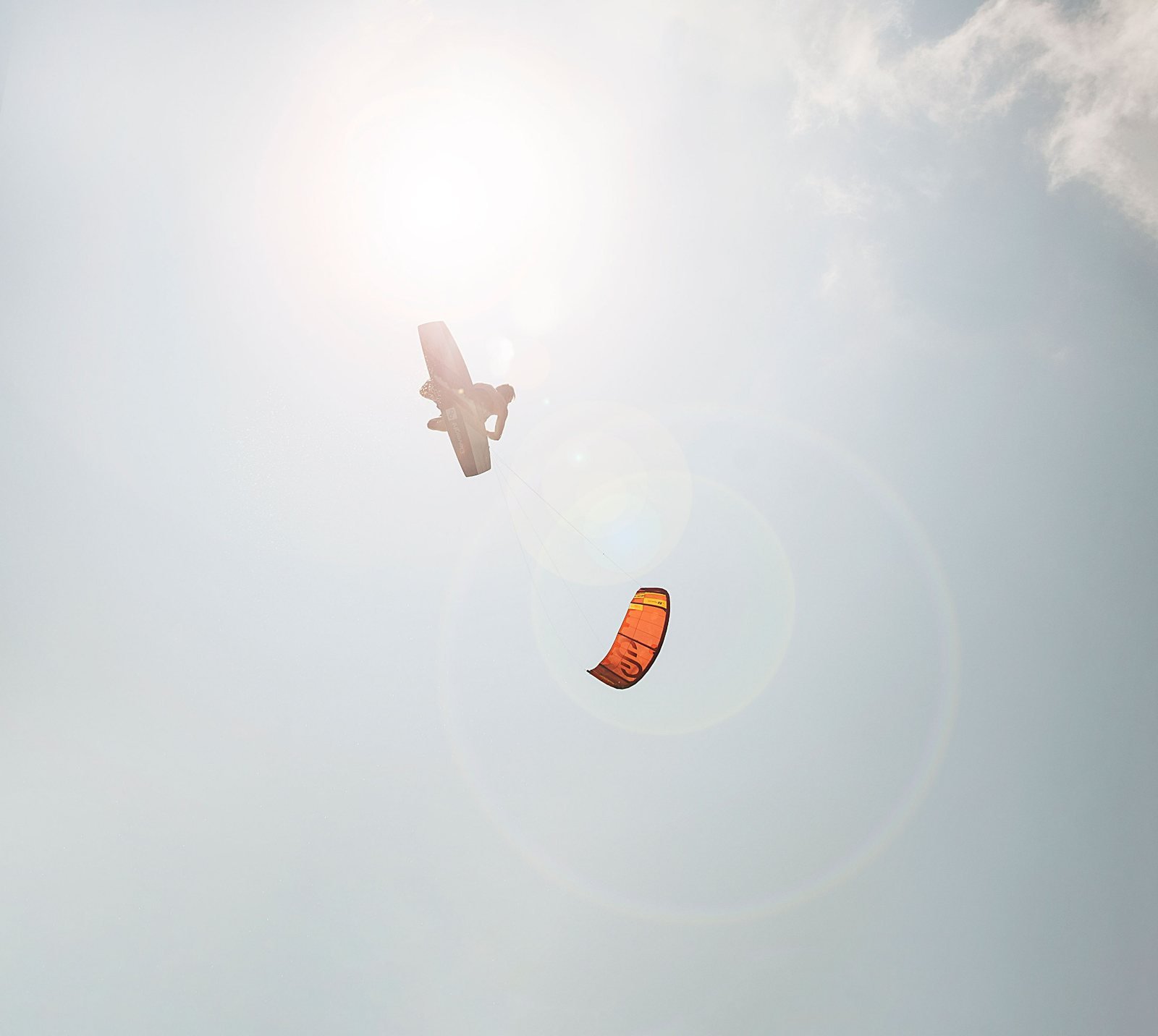Kiteboarder silhouetted against the sun during a jump