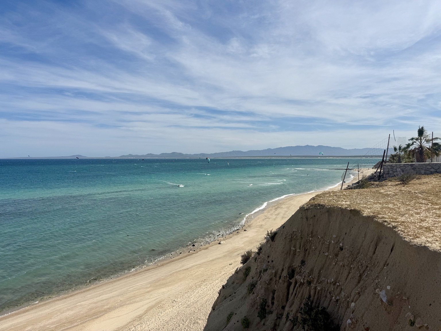Turquoise water, sandy coastline, and kiteboarders in La Ventana, Mexico