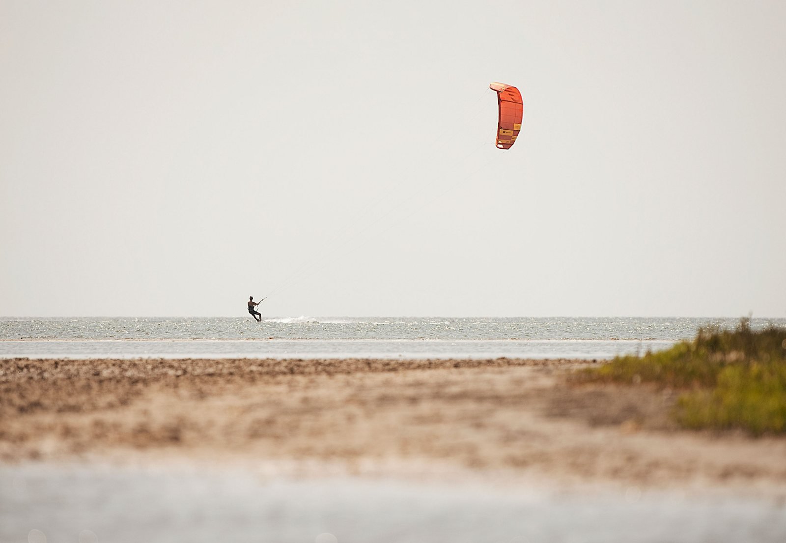 Orange kite flying over the shoreline
